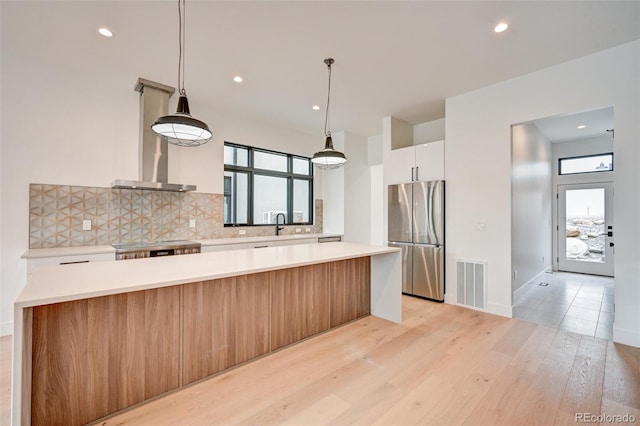 kitchen with white cabinets, a kitchen island, stainless steel appliances, and light wood-type flooring