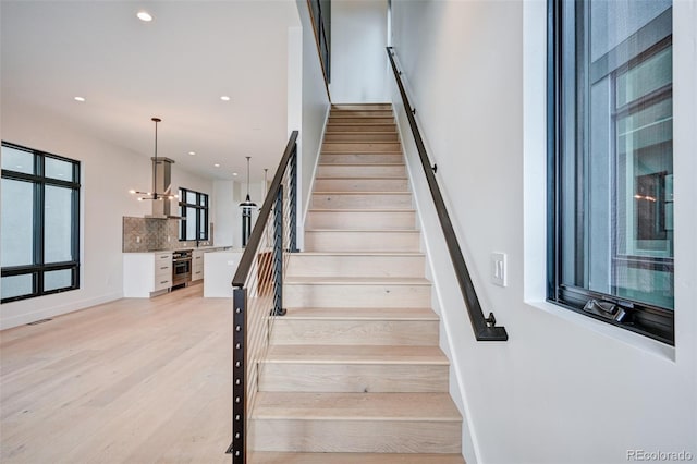 stairs with hardwood / wood-style floors and a chandelier