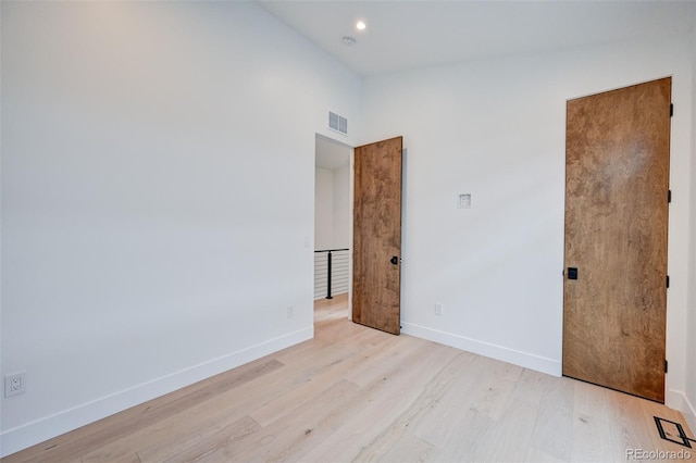 spare room with a towering ceiling and light hardwood / wood-style floors