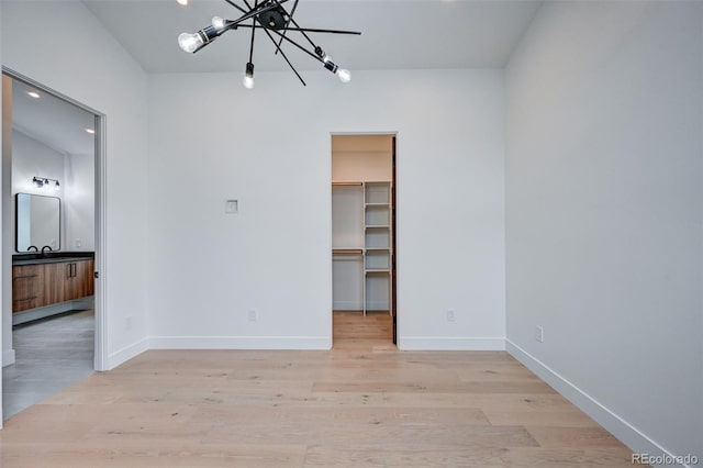 spare room featuring light wood-type flooring, sink, and an inviting chandelier