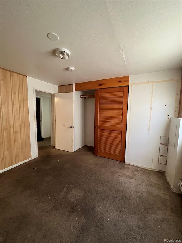 unfurnished bedroom featuring dark carpet and wood walls