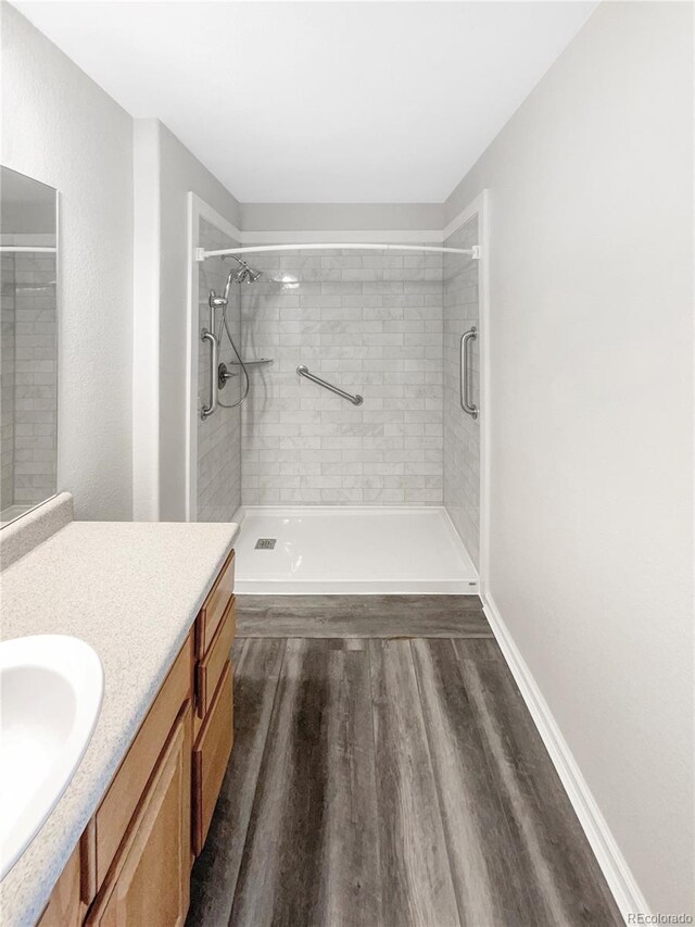 bathroom with wood-type flooring, a shower with shower door, and vanity