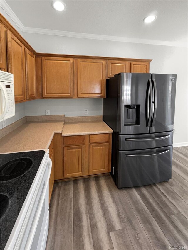 kitchen with hardwood / wood-style floors, white appliances, and ornamental molding