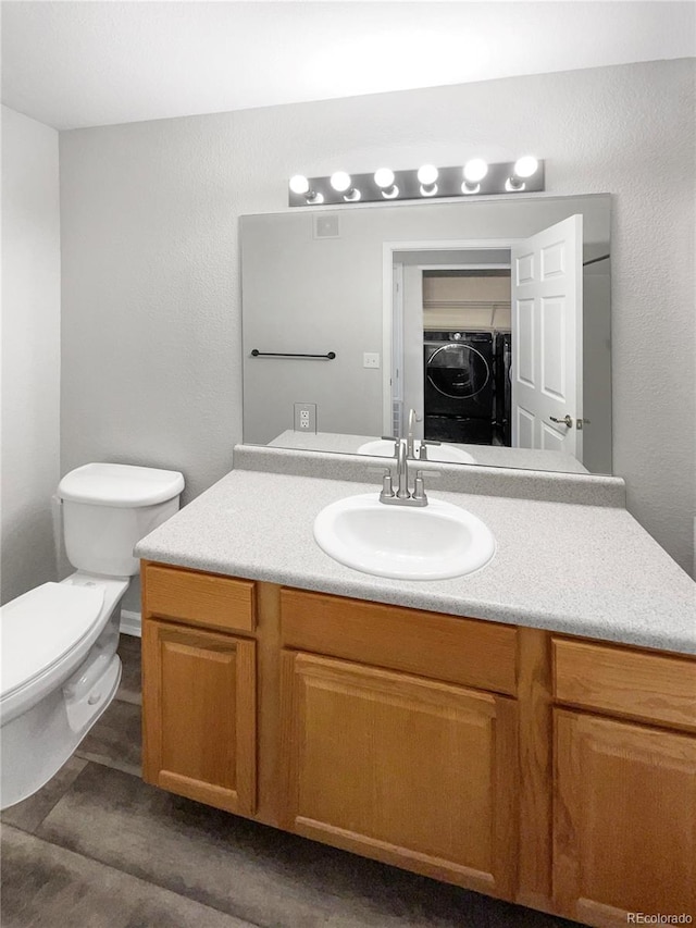 bathroom with vanity, toilet, and washing machine and clothes dryer