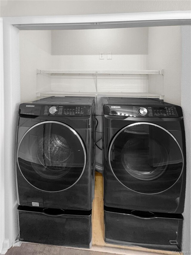 clothes washing area with separate washer and dryer and wood-type flooring