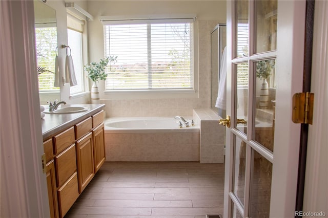 698 Larimer Creek Dr, Monument, CO 80132 - full bathroom featuring vanity, healthy amount of natural light, a garden tub, and hardwood / wood-style floors