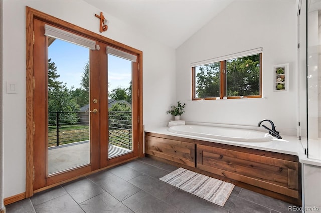 full bathroom featuring lofted ceiling, tile patterned floors, a bath, and a healthy amount of sunlight