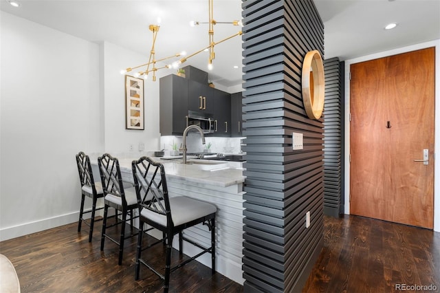 kitchen with sink, dark hardwood / wood-style flooring, kitchen peninsula, a breakfast bar area, and a chandelier