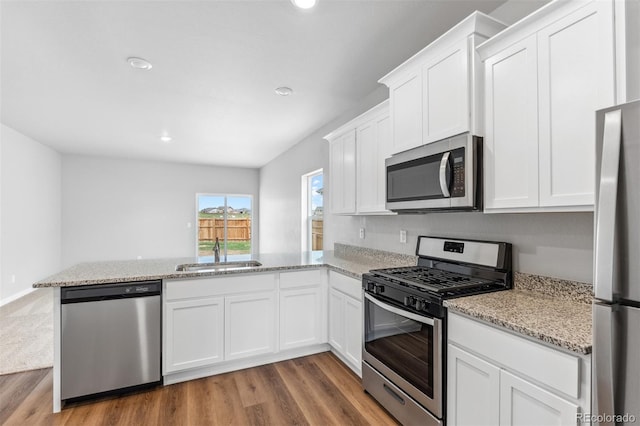 kitchen featuring kitchen peninsula, white cabinetry, sink, and appliances with stainless steel finishes