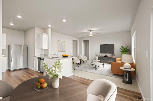 dining room with ceiling fan, light wood-type flooring, and sink