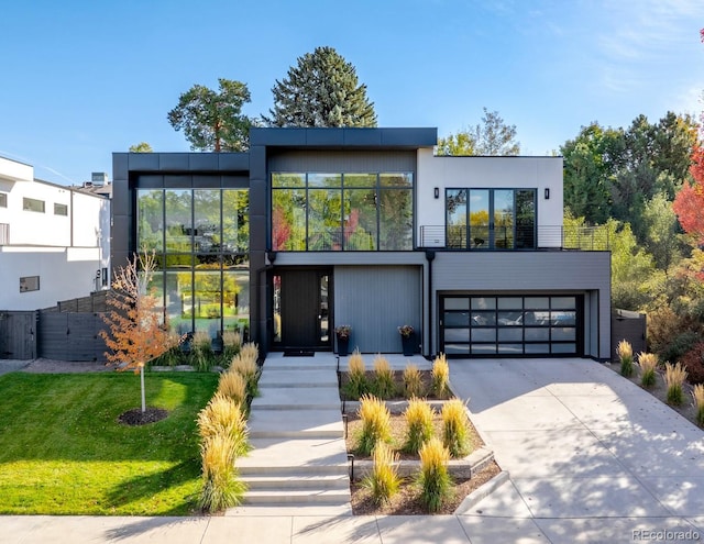 view of front of home with concrete driveway, a front yard, a balcony, and an attached garage