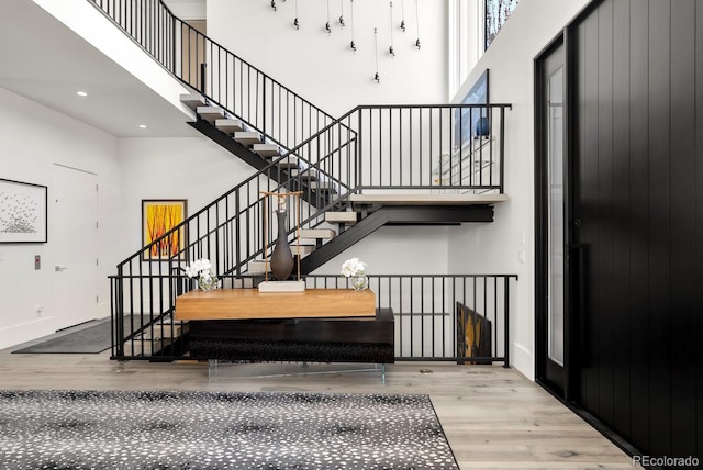 stairs featuring baseboards, recessed lighting, a high ceiling, and wood finished floors