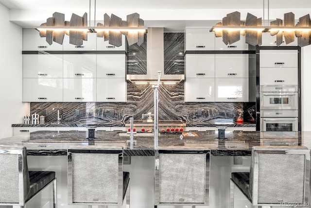 kitchen featuring a kitchen bar, backsplash, modern cabinets, and white cabinets