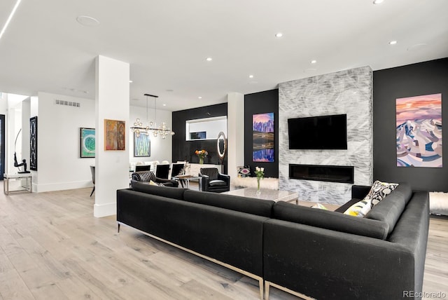 living room with visible vents, an inviting chandelier, light wood-style floors, recessed lighting, and a large fireplace