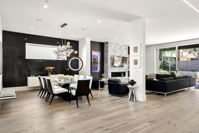 dining space with recessed lighting, a fireplace, light wood-type flooring, and an inviting chandelier