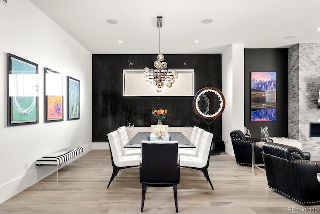 dining room with a notable chandelier, baseboards, recessed lighting, an accent wall, and light wood finished floors