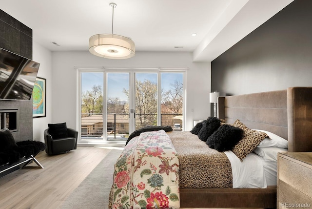 bedroom featuring access to outside, wood finished floors, a fireplace, and recessed lighting