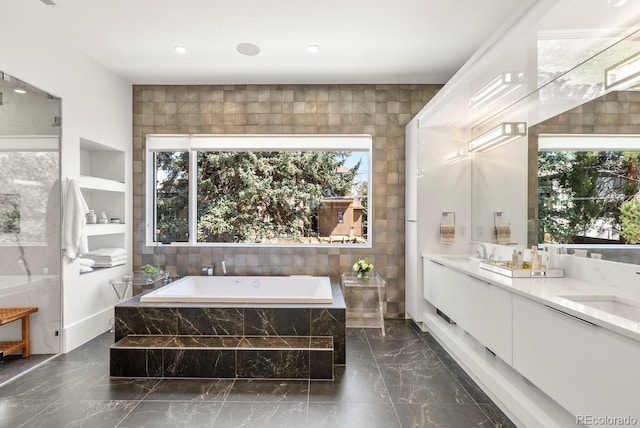full bathroom with a sink, a wealth of natural light, marble finish floor, and a garden tub