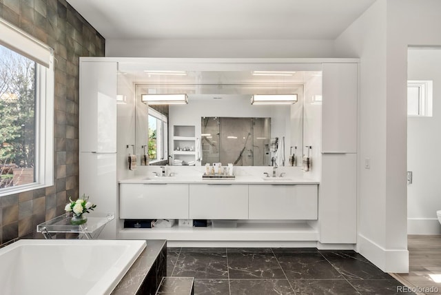 bathroom with a sink, double vanity, a stall shower, and tiled tub