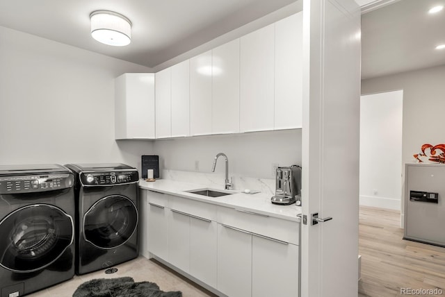 washroom with separate washer and dryer, baseboards, light wood-style flooring, cabinet space, and a sink
