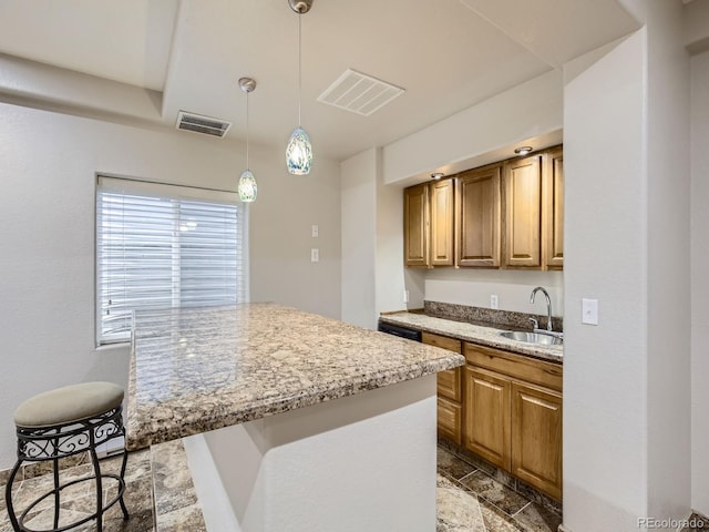 14310 Kalamath St, Westminster, CO 80023 - kitchen featuring stone tile flooring, light stone counters, decorative light fixtures, a kitchen bar, and brown cabinets