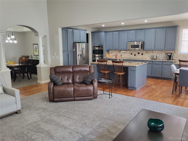 14310 Kalamath St, Westminster, CO 80023 - living room with decorative columns, arched walkways, light wood-type flooring, a high ceiling, and recessed lighting