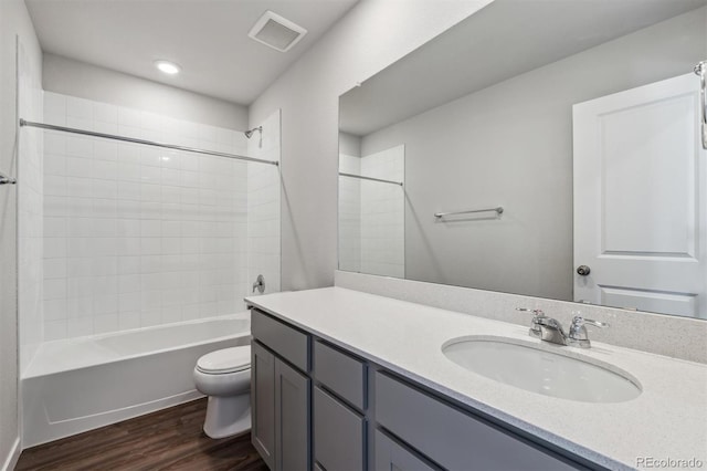 full bathroom with hardwood / wood-style flooring, vanity, tiled shower / bath combo, and toilet