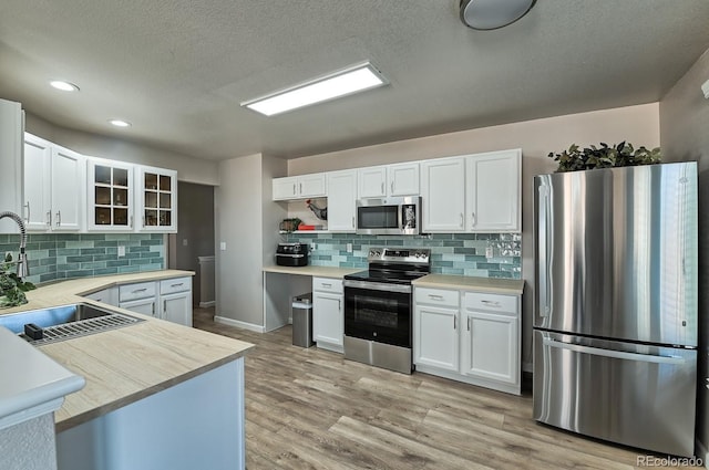 kitchen with appliances with stainless steel finishes, light hardwood / wood-style floors, white cabinetry, and sink