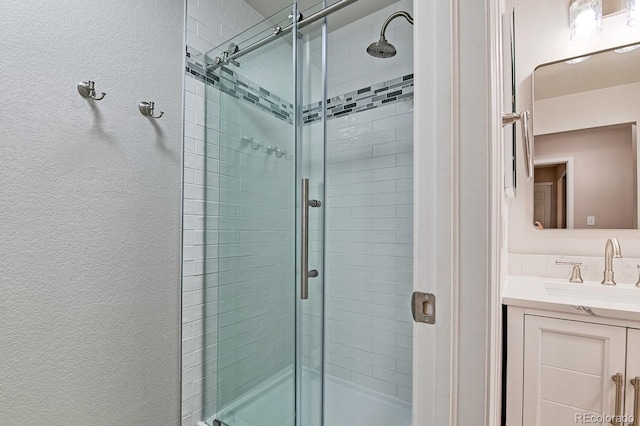 6475 Orion Way, Arvada, CO 80007 - bathroom featuring a shower stall, a textured wall, and vanity