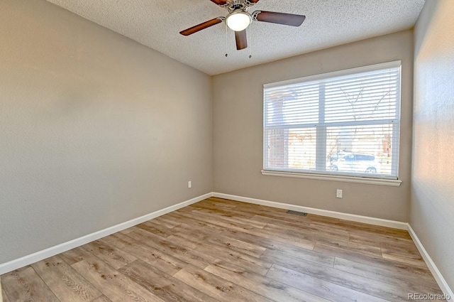 spare room with a textured ceiling, light hardwood / wood-style flooring, and ceiling fan