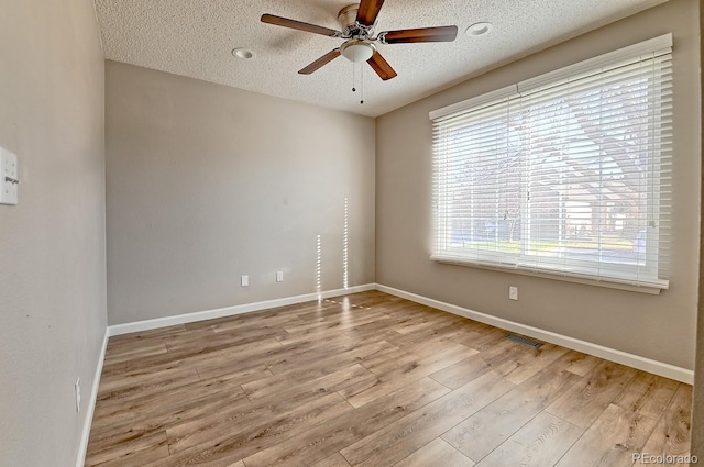 empty room featuring a textured ceiling, light hardwood / wood-style floors, and ceiling fan