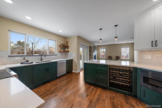 kitchen featuring appliances with stainless steel finishes, decorative light fixtures, dark wood-type flooring, sink, and green cabinets