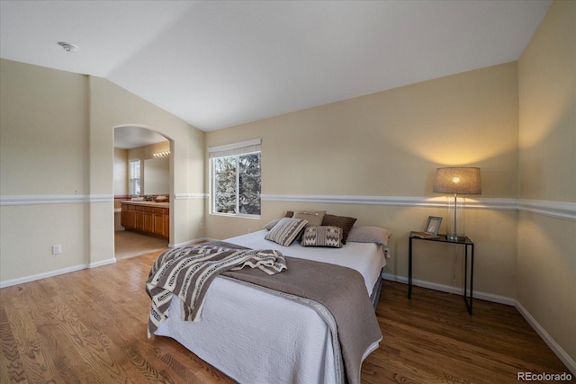 bedroom with ensuite bathroom, wood-type flooring, and lofted ceiling