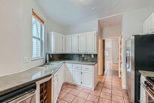 kitchen featuring sink, white cabinetry, a textured ceiling, stainless steel appliances, and decorative backsplash