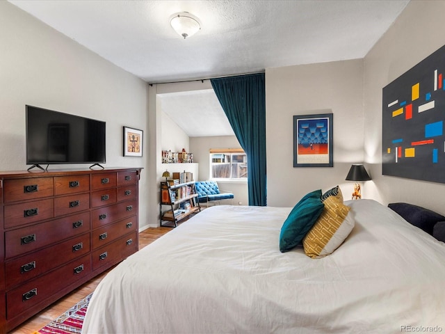 bedroom featuring lofted ceiling and light hardwood / wood-style floors