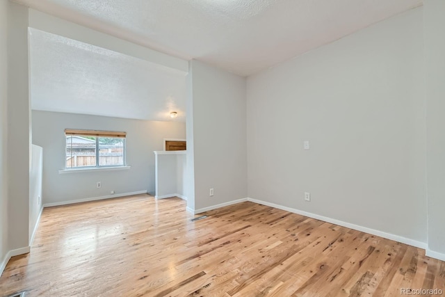 spare room featuring a textured ceiling and light wood-type flooring