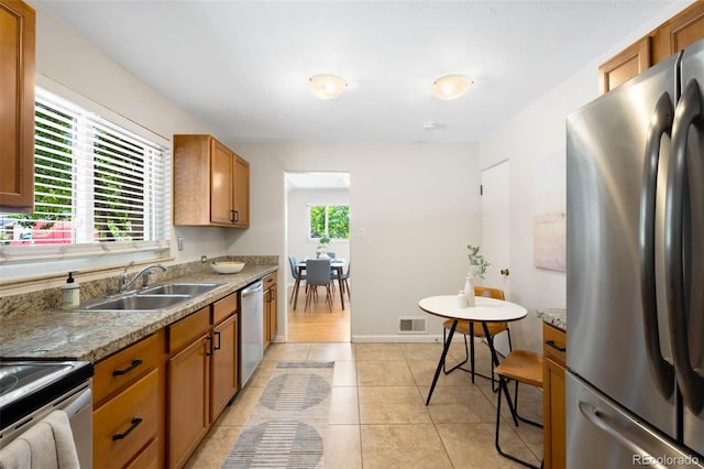 2900 Krameria St, Denver, CO 80207 - kitchen with appliances with stainless steel finishes, brown cabinetry, and light tile patterned floors