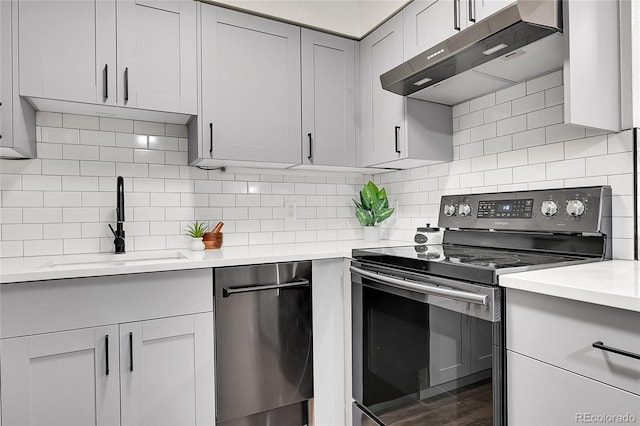 201 Wright St Unit 105, Lakewood, CO 80228 - kitchen featuring appliances with stainless steel finishes, under cabinet range hood, a sink, light countertops, and backsplash