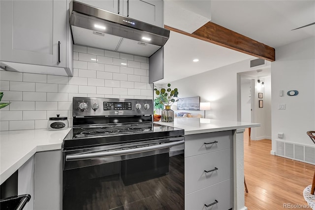 201 Wright St Unit 105, Lakewood, CO 80228 - kitchen featuring stainless steel electric range, under cabinet range hood, gray cabinets, light countertops, and beam ceiling