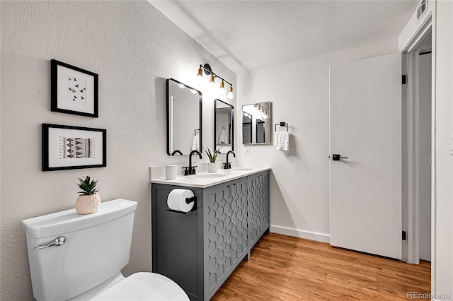 201 Wright St Unit 105, Lakewood, CO 80228 - bathroom featuring double vanity, toilet, wood finished floors, baseboards, and a textured ceiling