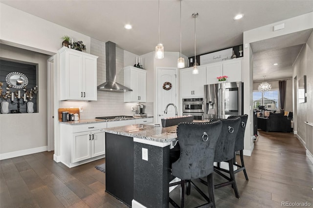10080 E 160th Pl, Brighton, CO 80602 - kitchen with wall chimney exhaust hood, a chandelier, appliances with stainless steel finishes, a kitchen bar, and dark wood finished floors