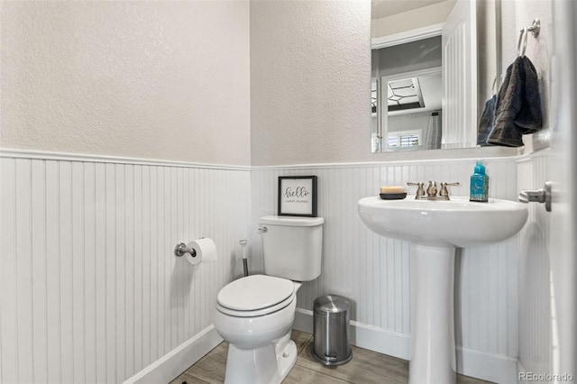 10080 E 160th Pl, Brighton, CO 80602 - bathroom with wood finished floors, toilet, a wainscoted wall, a textured wall, and a sink