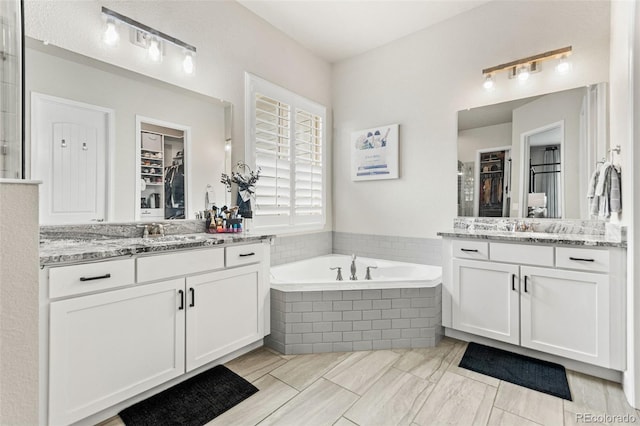 10080 E 160th Pl, Brighton, CO 80602 - bathroom featuring two vanities, a bath, and a walk in closet