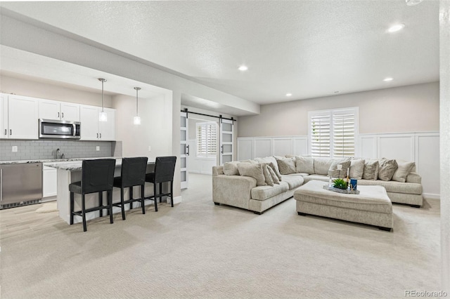 10080 E 160th Pl, Brighton, CO 80602 - living area featuring a barn door, light colored carpet, recessed lighting, a decorative wall, and a wainscoted wall