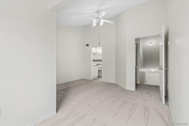 1631 Egret Way, Superior, CO 80027 - spare room with light carpet, a ceiling fan, a high ceiling, and baseboards