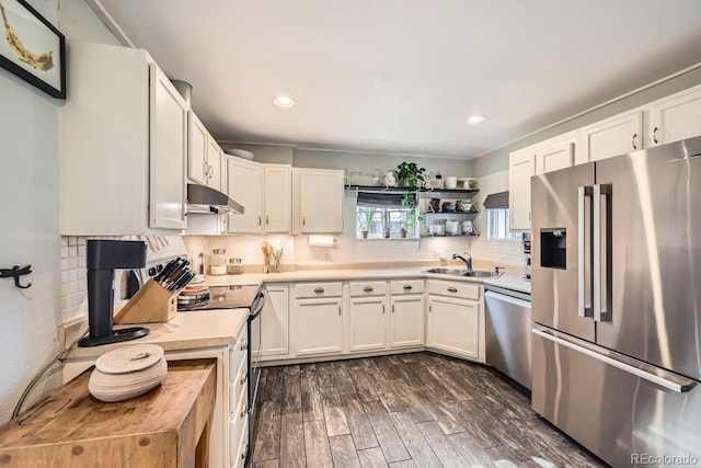 kitchen with appliances with stainless steel finishes, dark hardwood / wood-style floors, white cabinetry, sink, and decorative backsplash