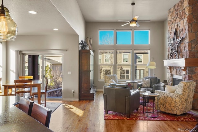 living room featuring hardwood / wood-style flooring, plenty of natural light, and a stone fireplace