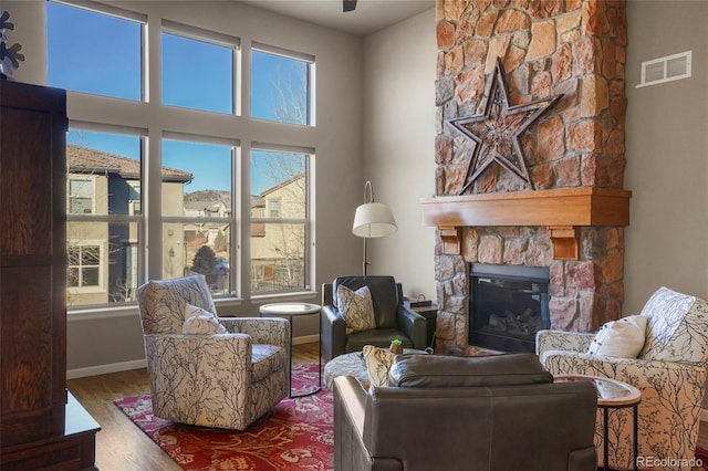 living room featuring hardwood / wood-style flooring, a towering ceiling, and a fireplace