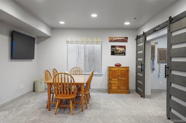 dining room featuring light carpet and a barn door