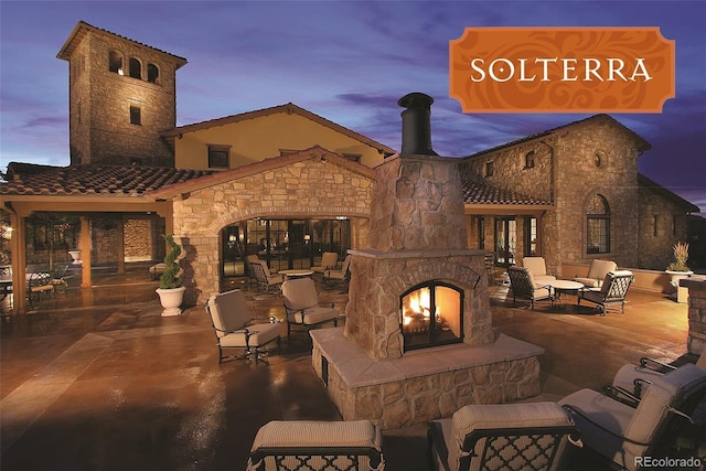 patio terrace at dusk featuring an outdoor living space with a fireplace